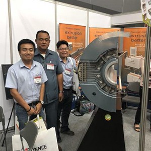 A group of men stand beside a large Container at a trade show.