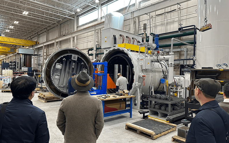 On lookers watch a man standing inside a large oven at the Heat Treat NewMarket Canada location.