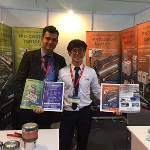 Two men stand showing booklets of products.